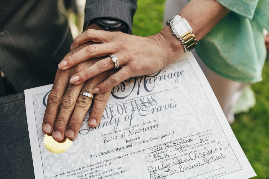 Amy and Xavier clasp hands holding marriage certificate - Amy Myers MD