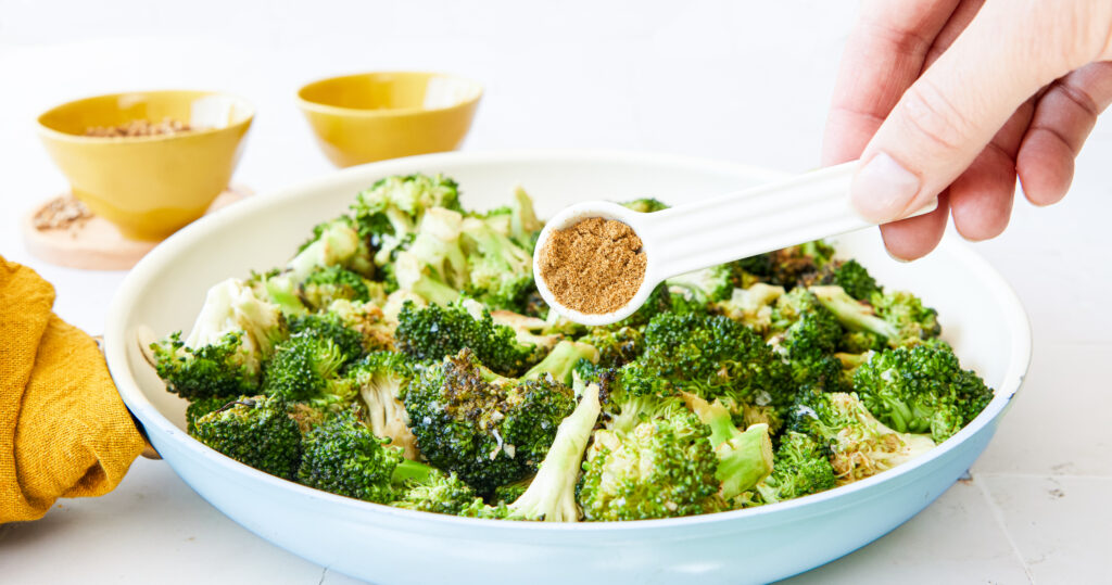 Adding cumin to the broccoli - Moroccan Spice Broccoli - Amy Myers MD®