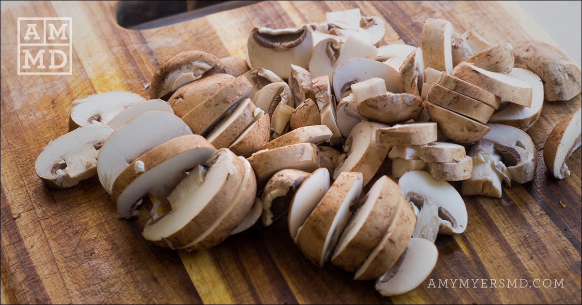Chopped mushrooms on top of a wooden cutting board for paleo meal prepping - Amy Myers MD®