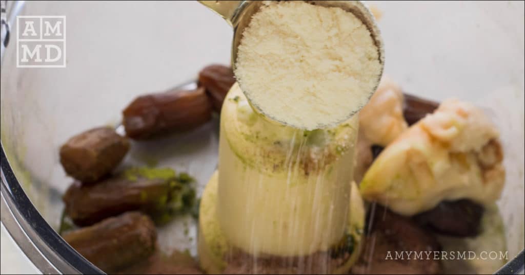 A scoop of coconut flour being added to a food processor with dates and coconut butter