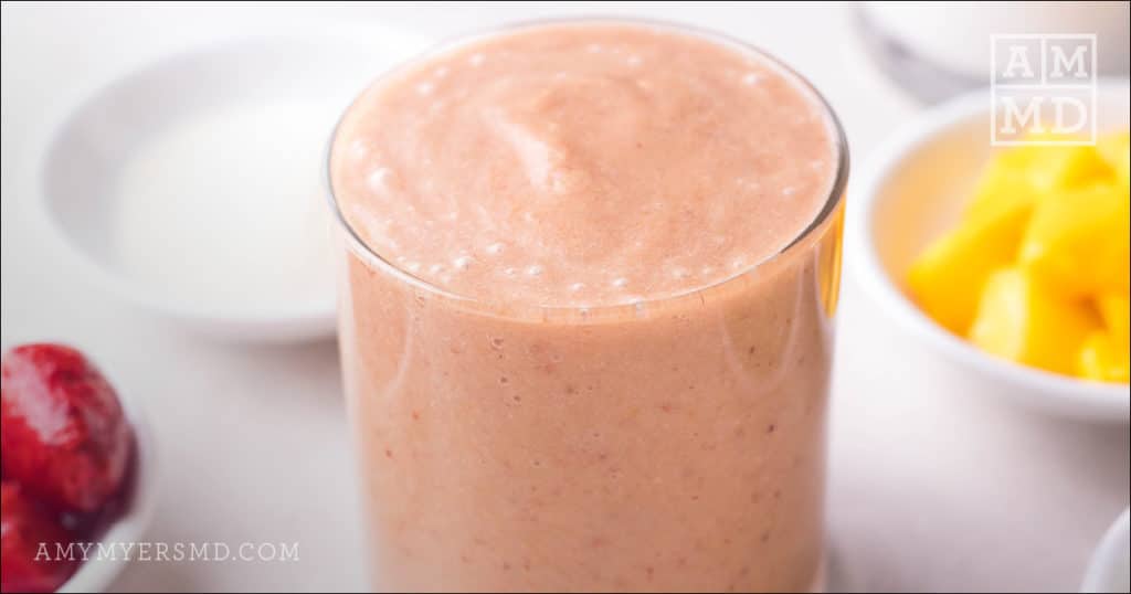 A tall glass of strawberry mango tropical smoothie made from Amy Myers Gut Recovery recipe eBook