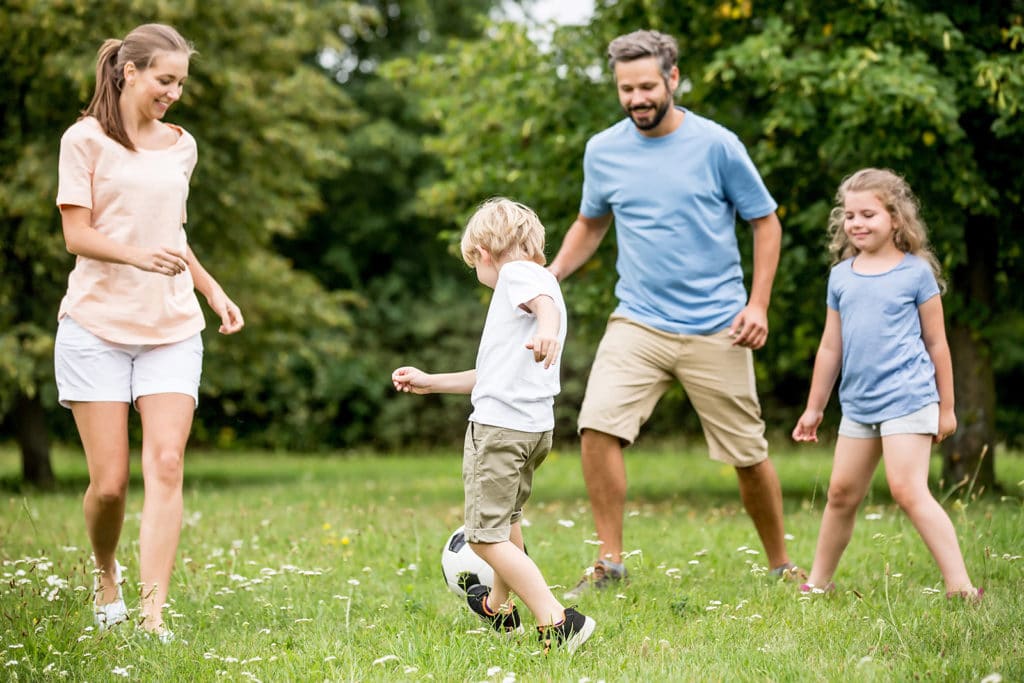 A family with young children playing Soccor