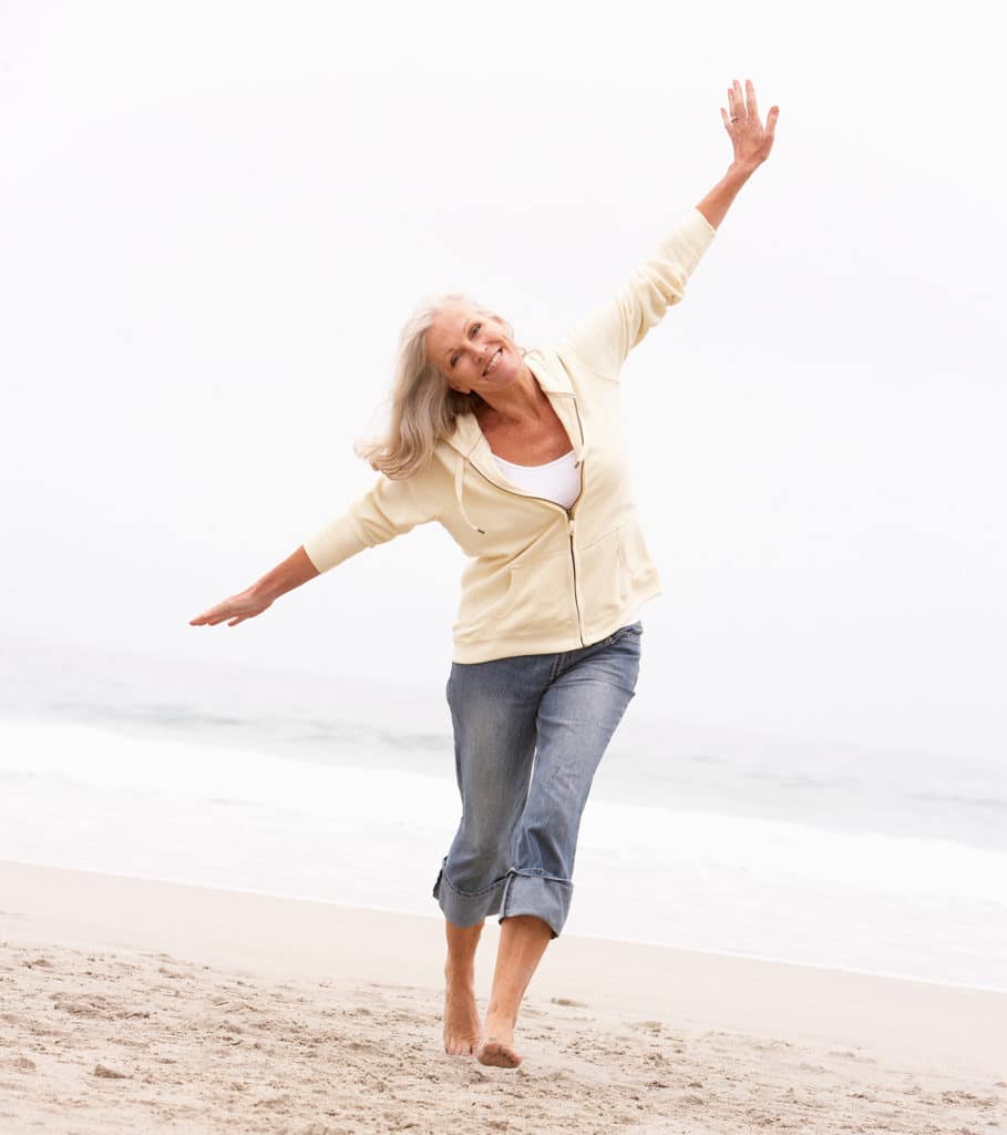 Woman in her 60s on a beach by the ocean enjoying life