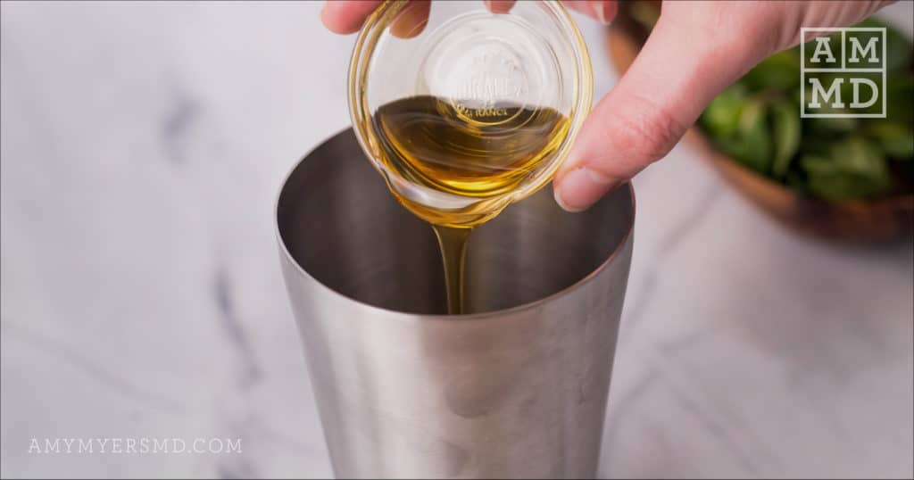 A tablespoon of agave syrup being added into a cocktail shaker