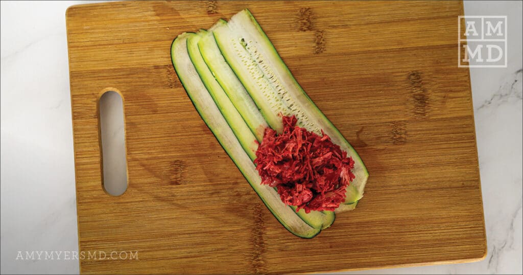 Sliced zucchini with shredded chicken on top of a wooden cutting board - Amy Myers MD®